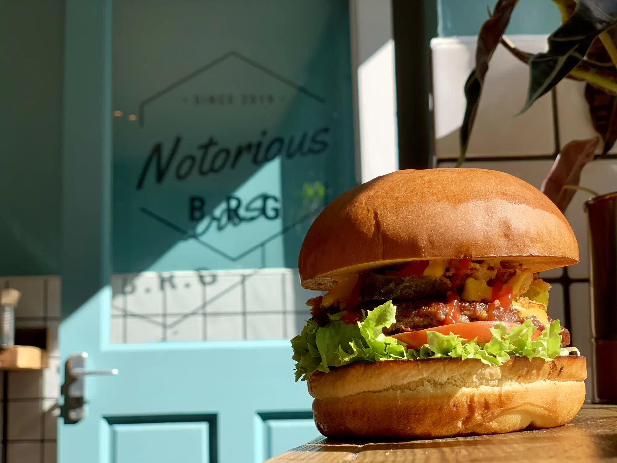 Burger on the counter in front of the teal Notorious B.R.G window lettering at Castle Street