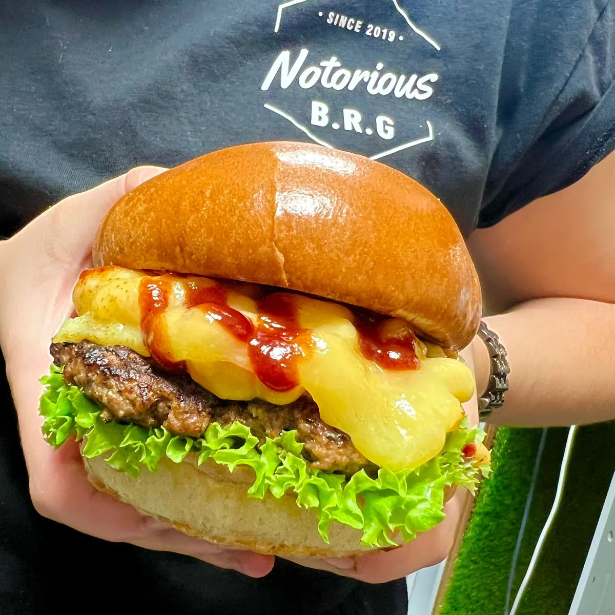 Team member in a Notorious B.R.G T-shirt holding a cheeseburger