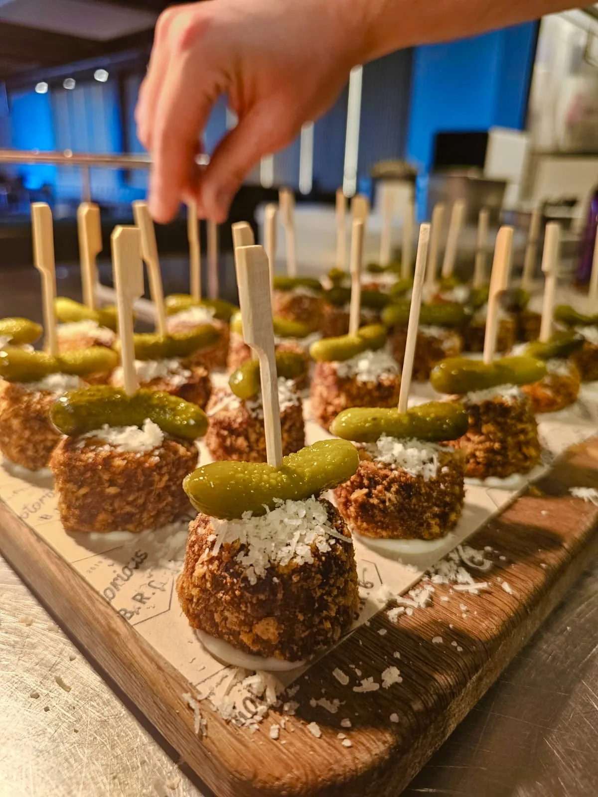 Pickle-topped crumbed bites on skewers, laid out by hand on a board for a private party in Kent
