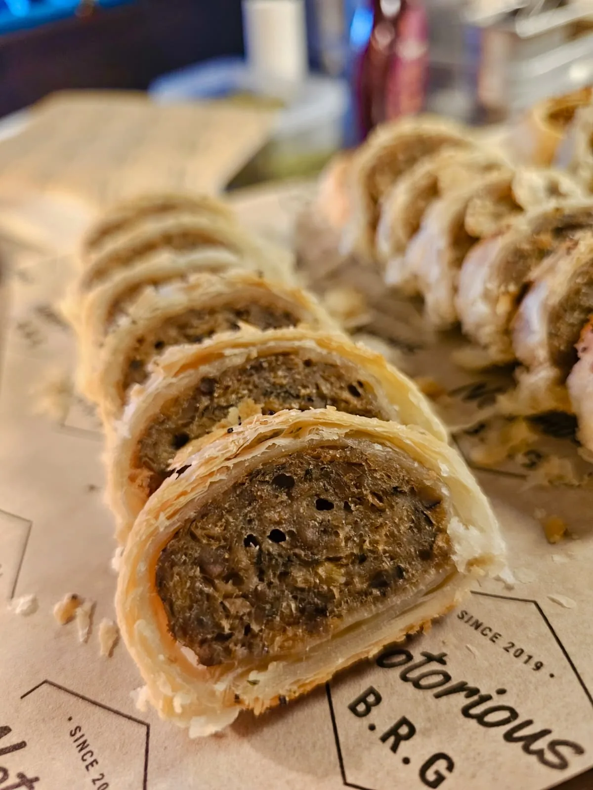 Slices of plant-based wellington on Notorious B.R.G paper, ready for a Kent buffet