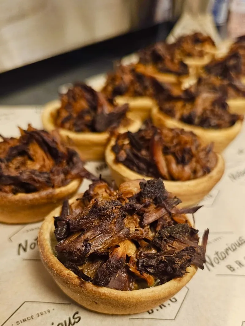Pulled meat tartlets lined up on Notorious B.R.G paper for a Canterbury party