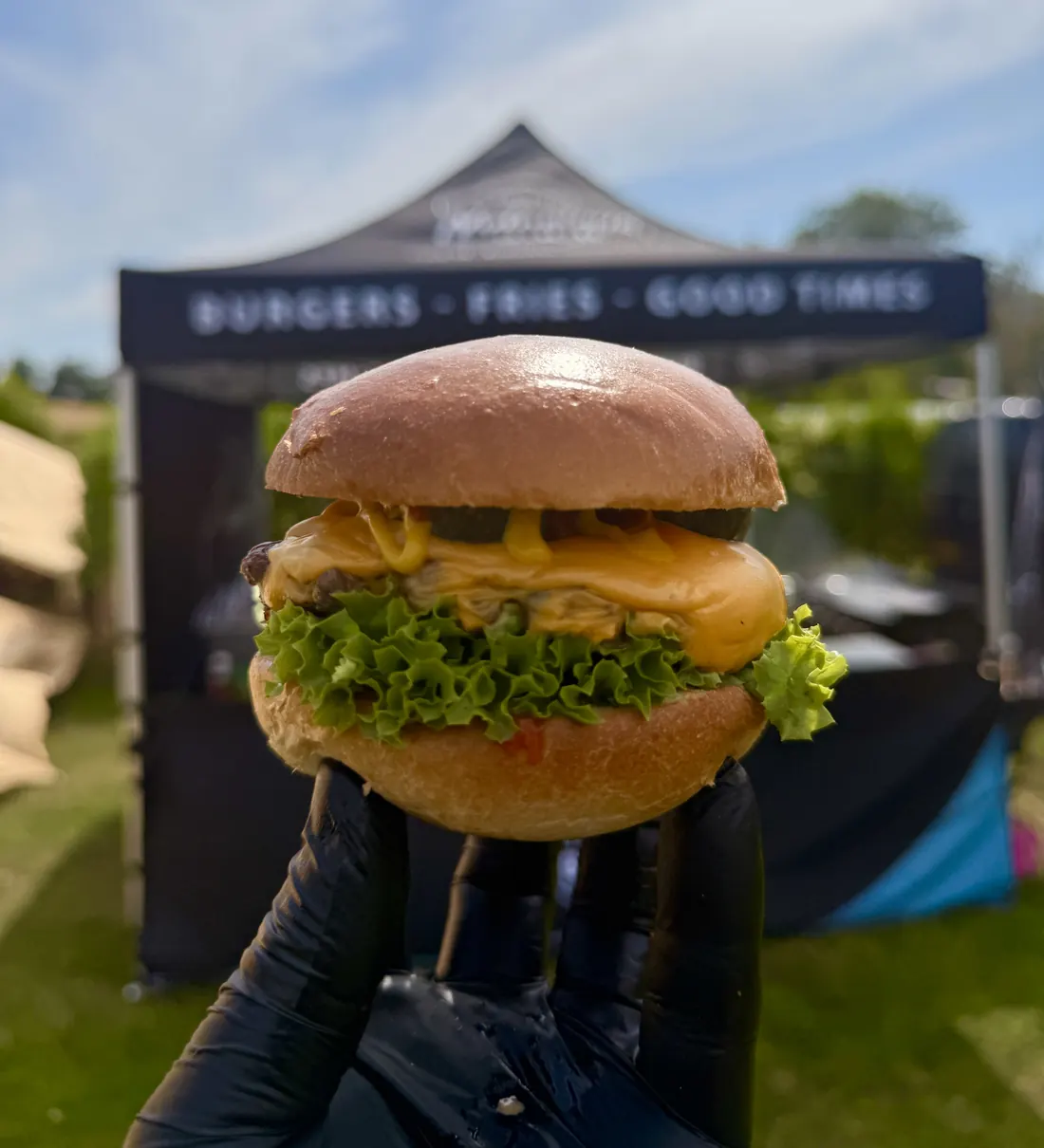 Smash burger held up in front of the Notorious Burgers, Fries, Good Times gazebo