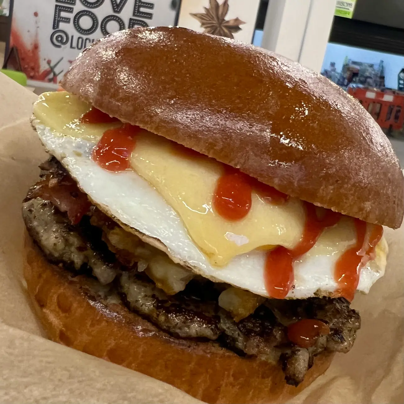 Double burger with a fried egg, Love Food signage behind